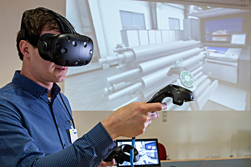 Mann mit VR-Datenbrille vor Projektion einer 3D-Landschaft